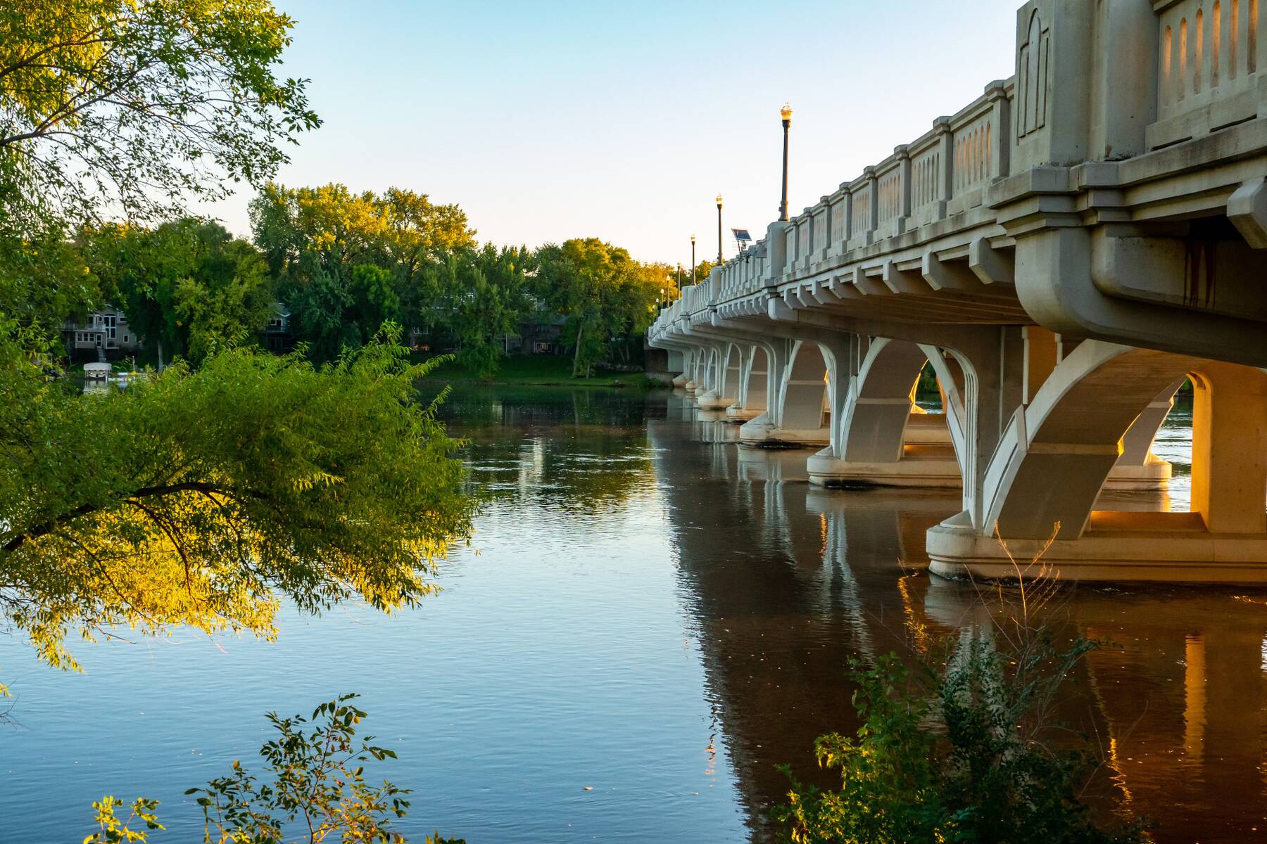A concrete arch bridge over the river at dusk